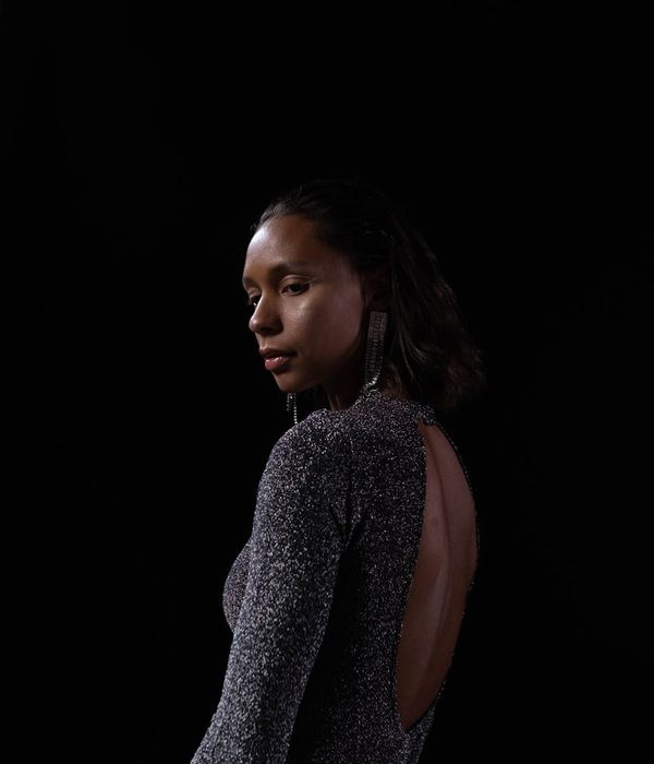 Woman in a calm yoga pose in a dark studio with emerald light.